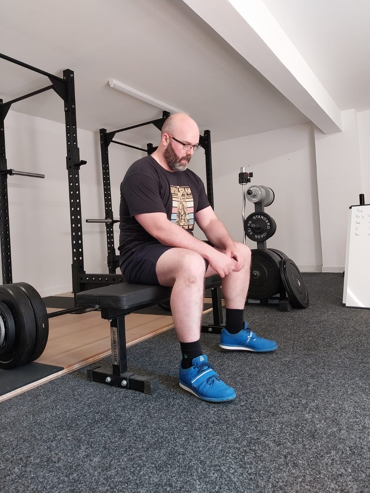 man sitting on a bench resting in between sets of squats